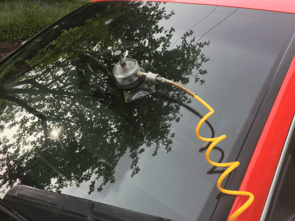 Close-up of car windshield chip marked for glass repair with reflection of trees"
